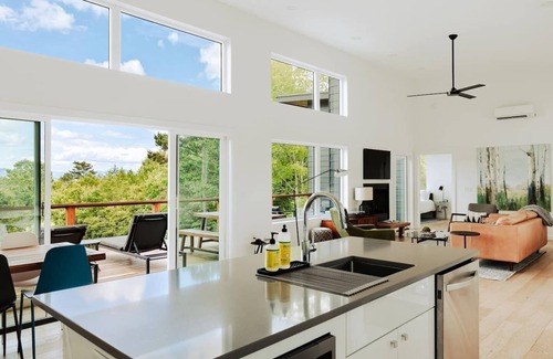 Young Harris Cabin | EcoModMtn is a 3BR/3.5BA luxury retreat with panoramic fall views, floor-to-ceiling windows, a gas fireplace, private hot tub, firepit, and designer kitchen. Perfect for families, couples, or friends seeking cozy mountain elegance this autumn.