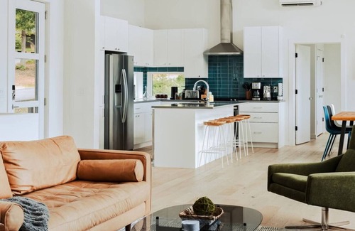 Young Harris Cabin | EcoModMtn is a 3BR/3.5BA luxury retreat with panoramic fall views, floor-to-ceiling windows, a gas fireplace, private hot tub, firepit, and designer kitchen. Perfect for families, couples, or friends seeking cozy mountain elegance this autumn.