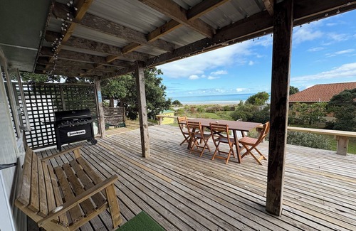 Ahipara House | Watch the waves from the large, sunny deck of this 1950's bach. Pet friendly.