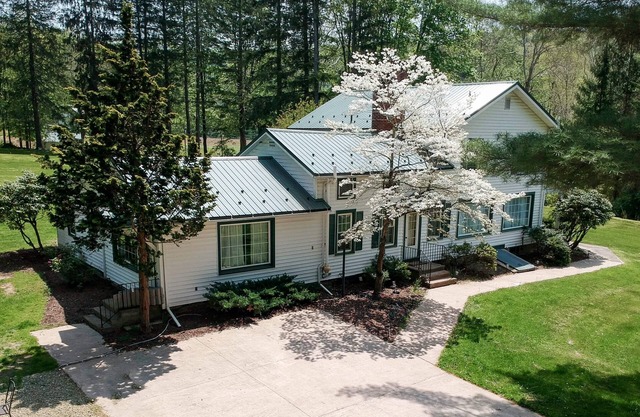 Creek side house with fireplace and concrete driveway.