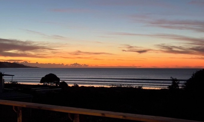 Ahipara House | Watch the waves from the large, sunny deck of this 1950's bach. Pet friendly.