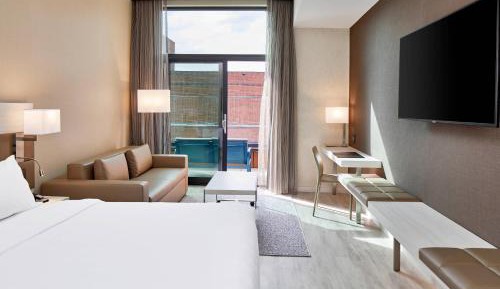 Guest room with king bed, sofa bed, balcony and city view